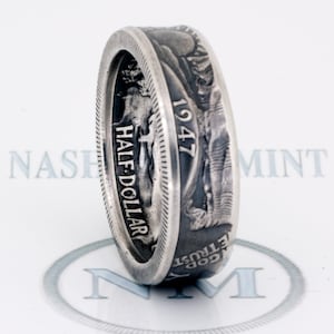 May include: A silver ring made from a 1947 half dollar coin. The ring features the inscription "HALF DOLLAR" and "IN GOD WE TRUST" on the side.