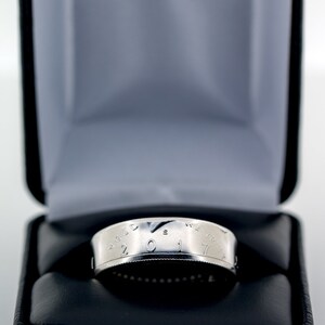 May include: A silver coin ring with the inscription "In God We Trust" and the year "2017" on the band. The ring is displayed in a black velvet ring box.