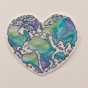 May include: A heart-shaped embroidered patch with a blue, green, and purple world map design.