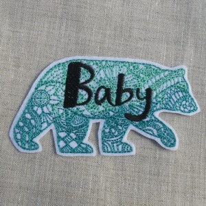 May include: Green and white embroidered bear patch with the word "Baby" in black lettering.
