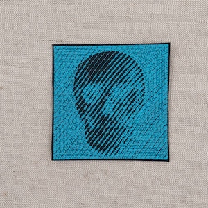 Könnte beinhalten: Ein gestickter Patch in Schwarz und Blau mit einem Totenkopf-Motiv.