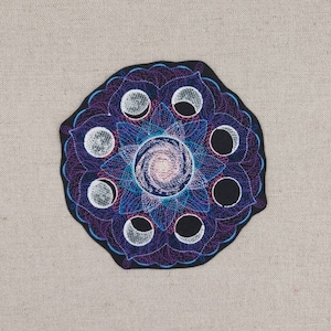 Könnte beinhalten: Ein schwarzer gestickter Patch mit einem Mandala-Design in Lila und Blau, das die acht Mondphasen zeigt.