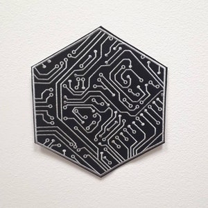 Könnte beinhalten: Ein schwarzer sechseckiger Patch mit einem weißen gestickten Schaltkreisdesign.