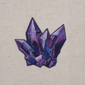 Könnte beinhalten: Lila und blauer gestickter Kristall-Patch. Der Patch hat die Form eines Kristallhaufens mit scharfen Kanten und einer strukturierten Oberfläche.