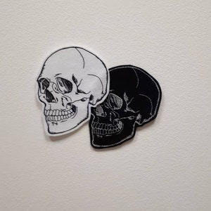 May include: Two embroidered skull patches, one white and one black, on a white background.