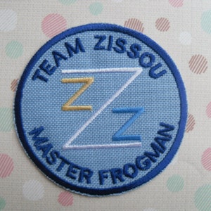 May include: Blue and white embroidered patch with the text "Team Zissou Master Frogman" and a stylized "Z" in the center.