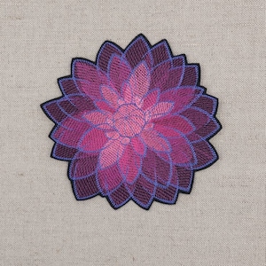 Op de afbeelding: Een geborduurde bloemenpatch in roze en paarse tinten met een zwarte omtrek.