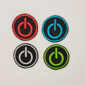 May include: Four round embroidered iron-on patches with a power button symbol. The patches are black with a red, blue, white, and green power button symbol.