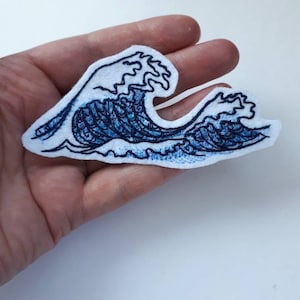 Könnte beinhalten: Blauer gestickter Wellen-Patch auf weißem Filzgrund. Die Welle ist stilisiert und hat ein traditionelles japanisches Design.