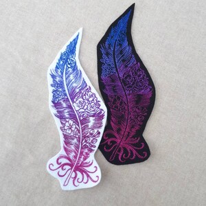 Peut inclure: Deux patchs brodés thermocollants représentant une plume ombrée de violet et de bleu avec des détails floraux. Un patch est sur fond blanc et l'autre sur fond noir.