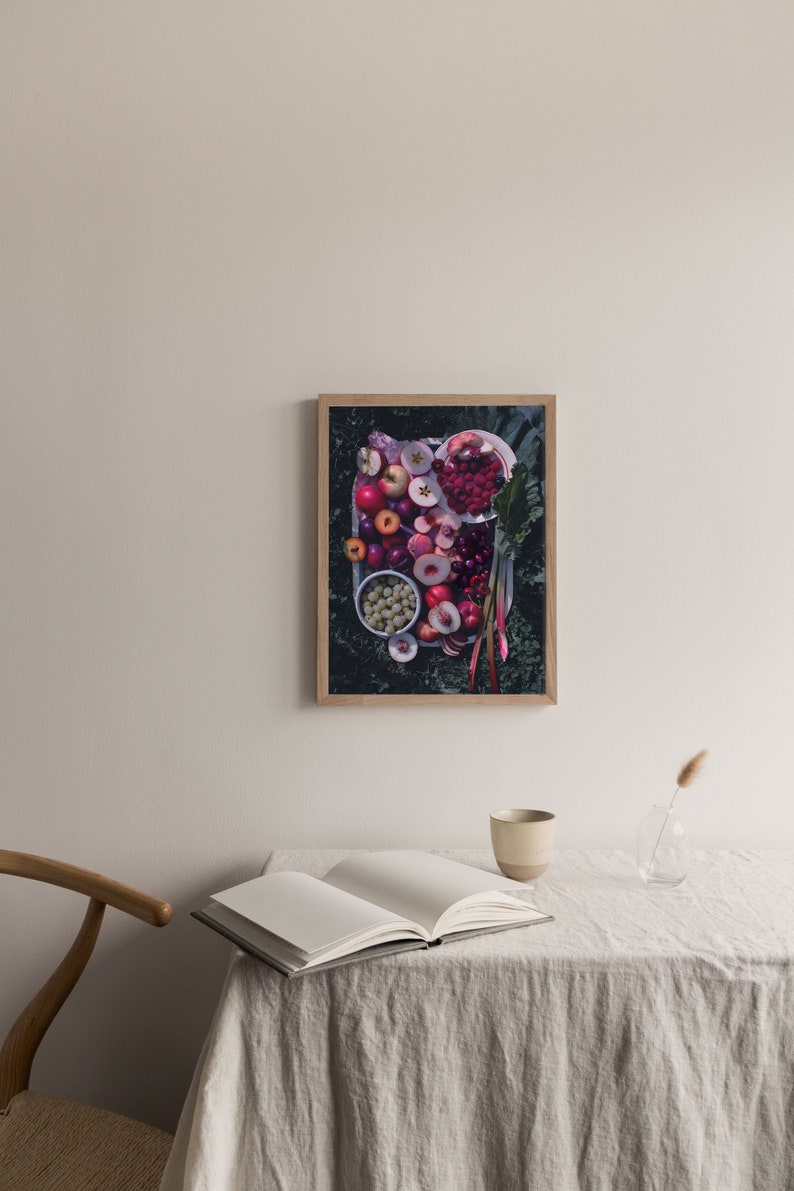 May include: A framed photograph of a platter of fruit, including red apples, plums, cherries, and peaches, arranged on a bed of green leaves.