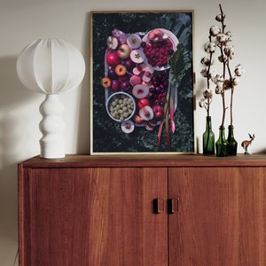 May include: A framed print of a still life featuring a variety of fresh fruit, including peaches, cherries, raspberries, and grapes, arranged on a white plate. The fruit is surrounded by green leaves and stems.