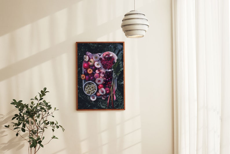 May include: A framed print of a still life featuring a variety of red and pink fruits, including apples, cherries, and plums, arranged on a plate with green leaves.