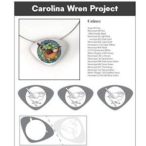 May include: A pendant necklace featuring a Carolina Wren design. The pendant is white with a detailed illustration of the bird in shades of brown, orange, and blue. The text "Carolina Wren Project" is at the top.