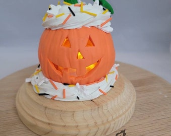 Jack-o'-lantern frosted cupcake pumpkin display piece with real LED light on pine wood base for Halloween. Fancy sprinkles.