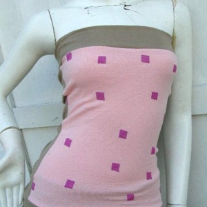 May include: A pink and brown strapless top with a square pattern. The top has a pink background with brown straps and a brown band at the bottom. The square pattern is in a light purple color.