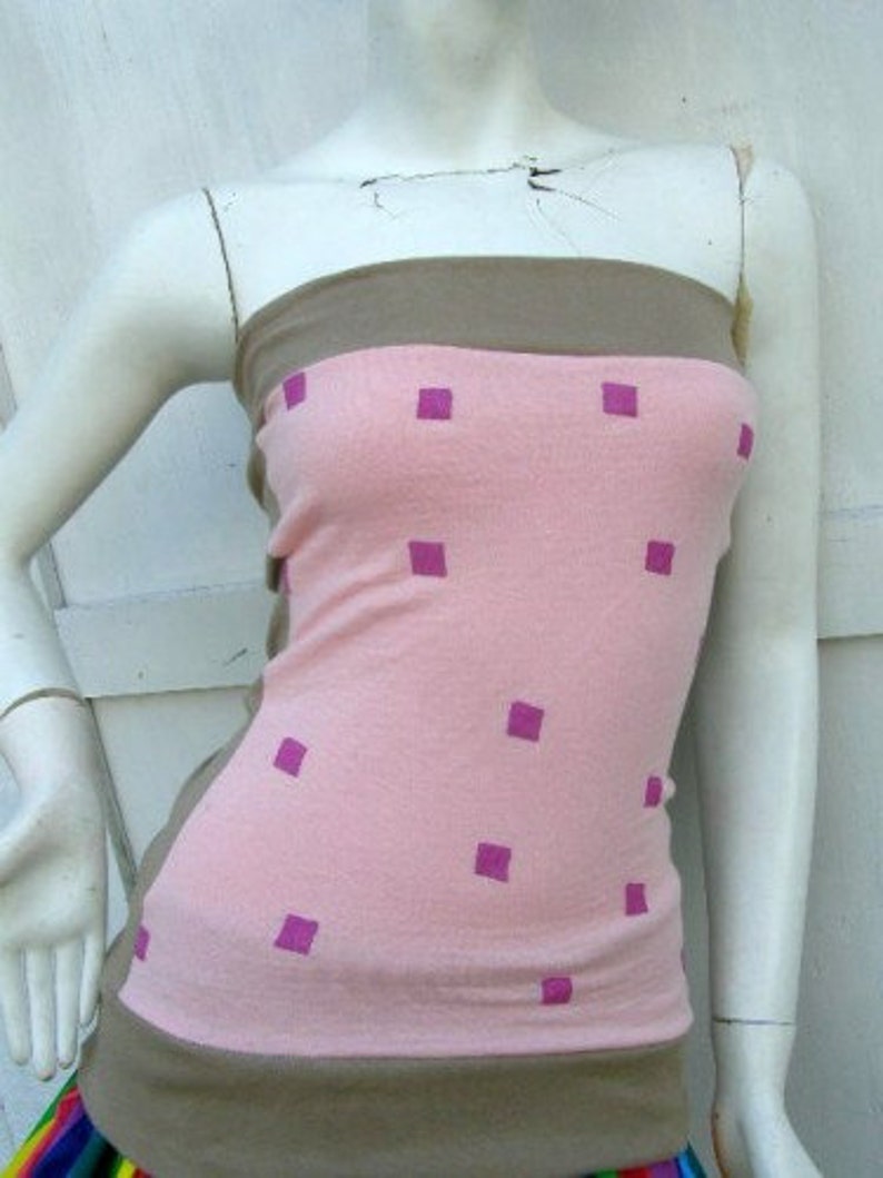 May include: A pink and brown strapless top with a square pattern. The top has a pink background with brown straps and a brown band at the bottom. The square pattern is in a light purple color.