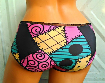 Puede incluir: Ropa interior de estilo patchwork negro y colorido con un patrón de lunares negros y blancos. La ropa interior tiene un borde de encaje negro.