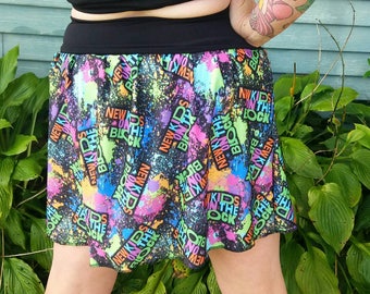 May include: A black skater skirt with a colorful paint splatter design featuring the words "New Kids on the Block" repeated throughout.