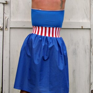 May include: A blue strapless dress with a red and white striped band around the waist.