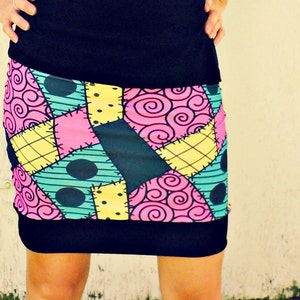 May include: A black and white patchwork skirt with a colourful pattern of pink, blue and yellow. The skirt has a black waistband and a black hem.