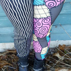 May include: Leggings with two different patterns. One leg features black and white vertical stripes, while the other has a patchwork design in pink, blue, gray, and beige. Black ankle boots with zippers complete the look.