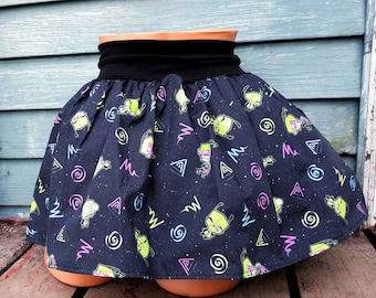 May include: A black skirt with a green alien print and a black elastic waistband. The skirt has a swirling pattern and a variety of shapes, including triangles and circles.