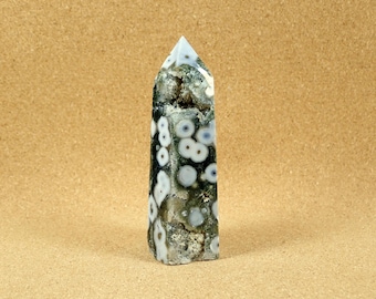 May include: A green and white ocean jasper crystal point with a pointed top and a smooth, polished surface.