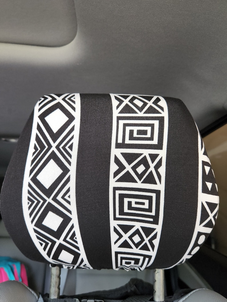 May include: Black and white geometric patterned car seat headrest cover. The pattern features a repeating design of squares, triangles, and lines.