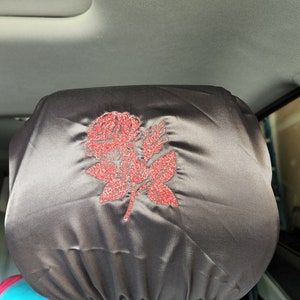 May include: A black satin car seat headrest cover with a red glitter rose design.