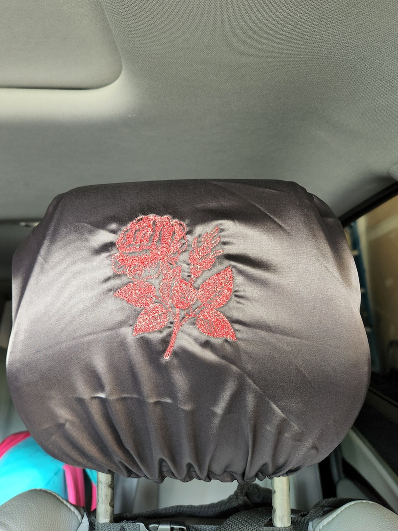 May include: A black satin car seat headrest cover with a red glitter rose design.