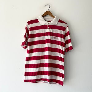 May include: Red and white striped short-sleeved polo shirt with a small logo that says "Bristol Flyers" on the chest.
