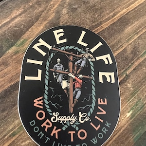 May include: Black and white oval sticker with the text "Line Life Work to Live Don't Live to Work" and a graphic of three people working on a power line. The text "Supply Co." is in the center of the sticker.