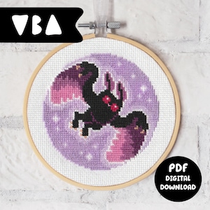 以下が含まれることがあります： 木製のフレームに入ったクロスステッチ刺繍。紫色の月の背景に、ピンクの翼を持つ黒い生き物が描かれています。「VBA」の文字が左上に、「PDF DIGITAL DOWNLOAD」の文字が右下にあります。