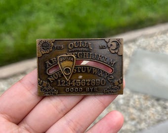 Pin esmaltado de tablero Ouija con planchette móvil