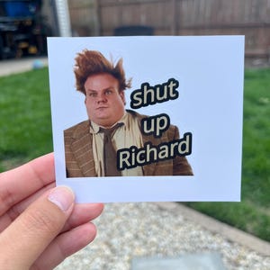 Puede incluir: Una pegatina rectangular con el retrato de un hombre de pelo casta&ntilde;o alborotado que lleva una americana de cuadros marr&oacute;n y corbata. El texto "shut up Richard" est&aacute; impreso en letras negras con un borde blanco a la derecha.