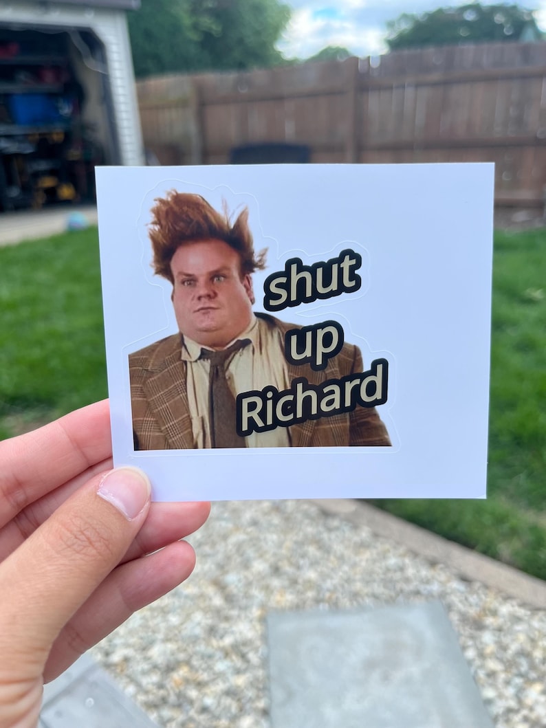 Puede incluir: Una pegatina rectangular con el retrato de un hombre de pelo casta&ntilde;o alborotado que lleva una americana de cuadros marr&oacute;n y corbata. El texto "shut up Richard" est&aacute; impreso en letras negras con un borde blanco a la derecha.
