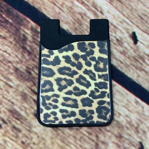 May include: Black phone grip with a leopard print design.