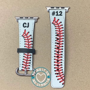 May include: Two white and red baseball-themed Apple Watch bands with black stitching. One band has the initials "CJ" and the other has the number "#12". Both bands have a silver buckle and a white background with red stitching.