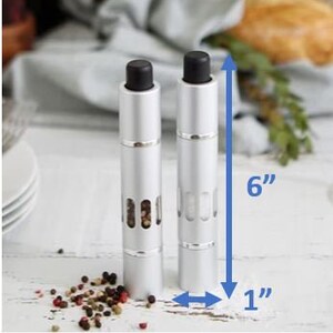 May include: Two silver pepper and salt grinders with black tops. The grinders are 6 inches tall and 1 inch in diameter.