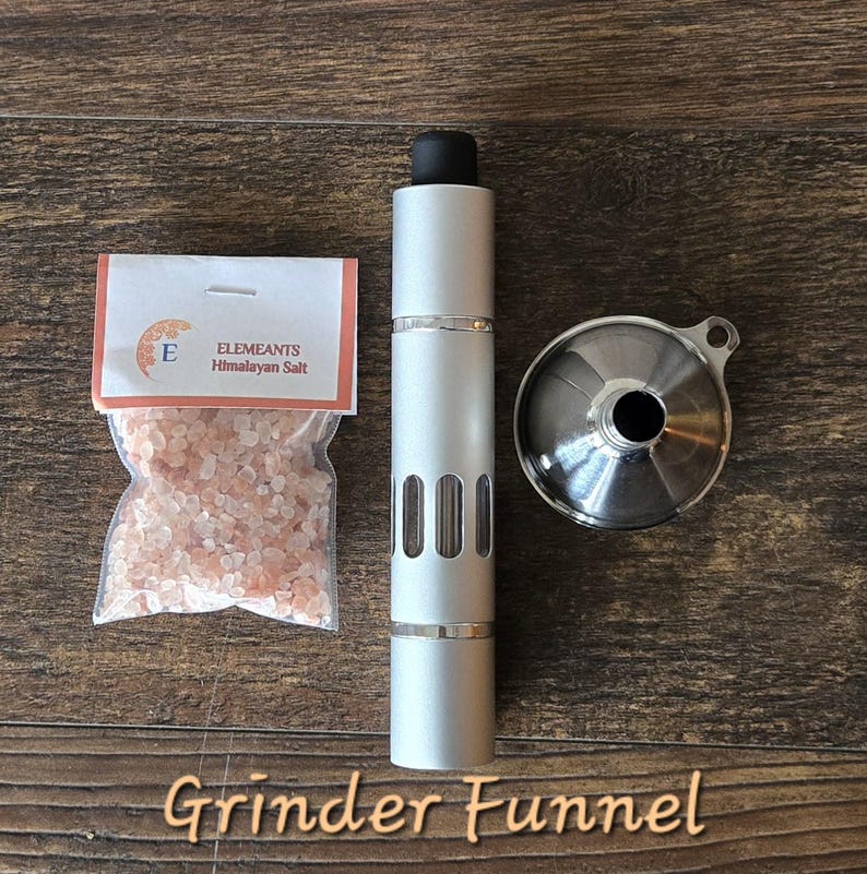 May include: A silver grinder and funnel for grinding Himalayan salt. The grinder has a clear window to see the salt inside. The package of salt is labeled "Elemeants Himalayan Salt".