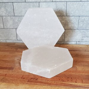 May include: Two white hexagonal Himalayan salt plates, one stacked on top of the other. The plates are smooth and have a slightly rough texture.