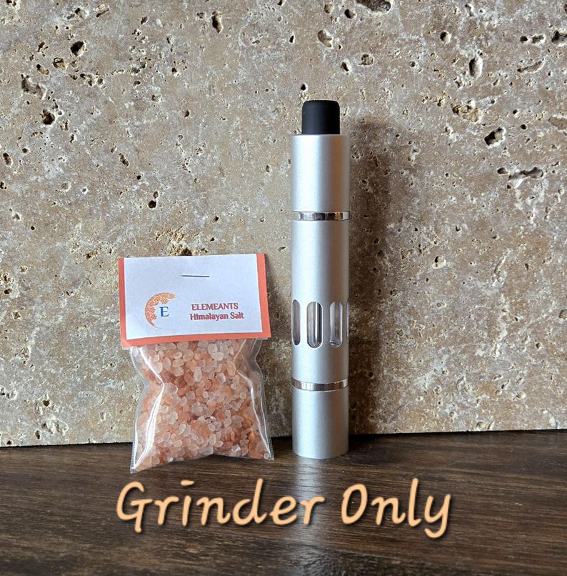 May include: A silver Himalayan salt grinder with a black top. The grinder is labeled "Elemeants Himalayan Salt".