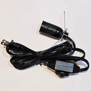 May include: A black electrical cord with a plug on one end, a light socket on the other end, and an in-line on/off switch.