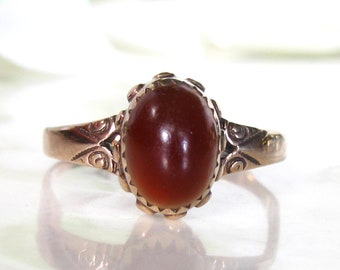 Puede incluir: Un anillo vintage con una piedra de cornalina roja engastada en un engaste de filigrana de oro.
