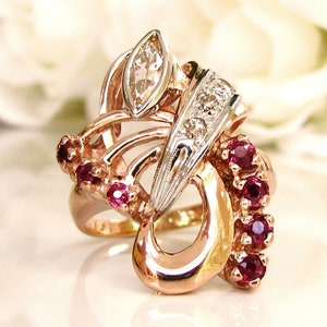 May include: A gold ring with a large marquise-shaped diamond and smaller diamonds set in a white gold band. The ring is adorned with a cluster of ruby stones.