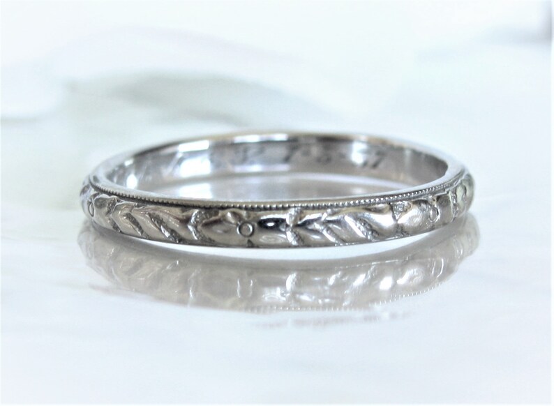 Puede incluir: Una banda de boda de plata con un delicado dise&ntilde;o floral grabado alrededor de la banda.