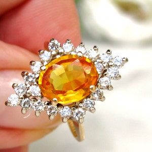 May include: A gold ring with a large oval-shaped orange gemstone surrounded by smaller white gemstones.
