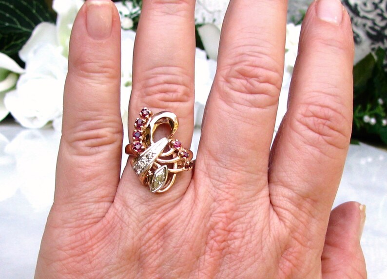 May include: A gold ring with a diamond and ruby stones set in a swirling design.