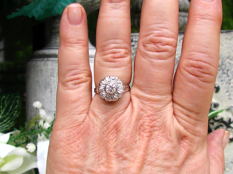 May include: A silver ring with a large round diamond surrounded by smaller diamonds.